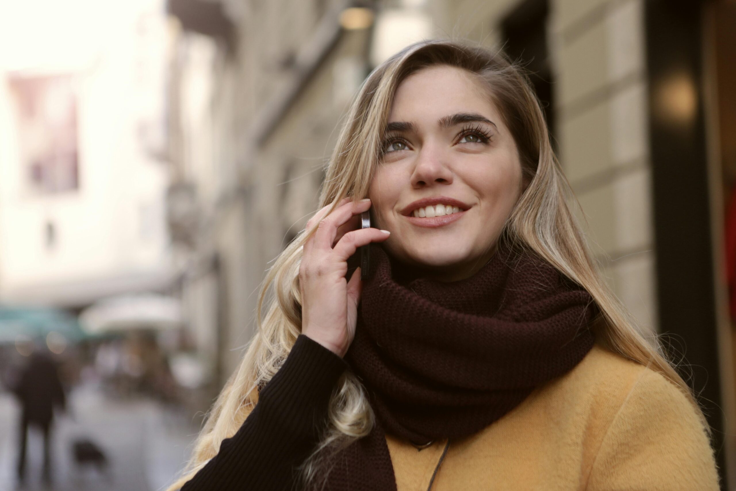 A woman talking on the phone and smiling after saving her tooth with endodontics (a root canal)